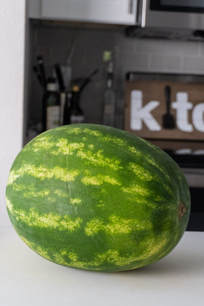 a small watermelon (whole) on a cutting board