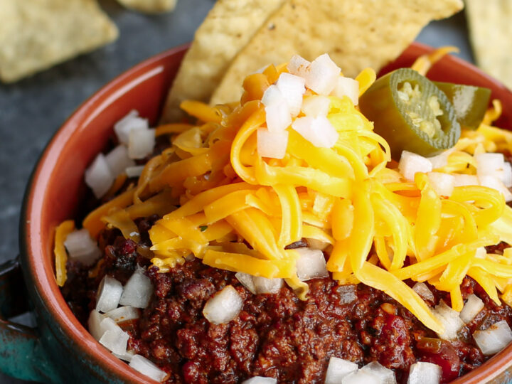 A bowl of bison chili topped with cheese and jalapeno peppers