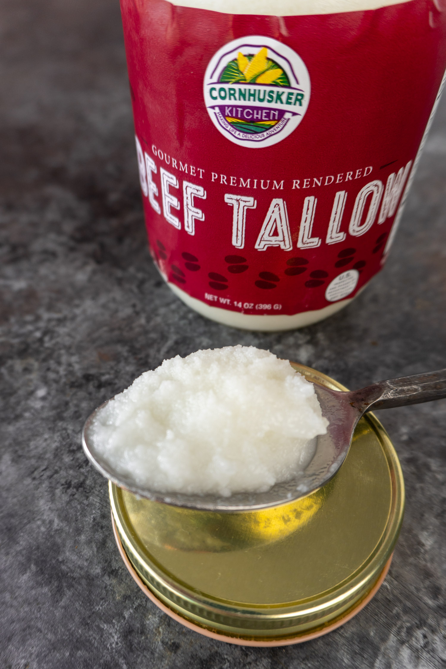 beef tallow in a spoon next to a jar: the new fat options avalable in specialty grocery stores.