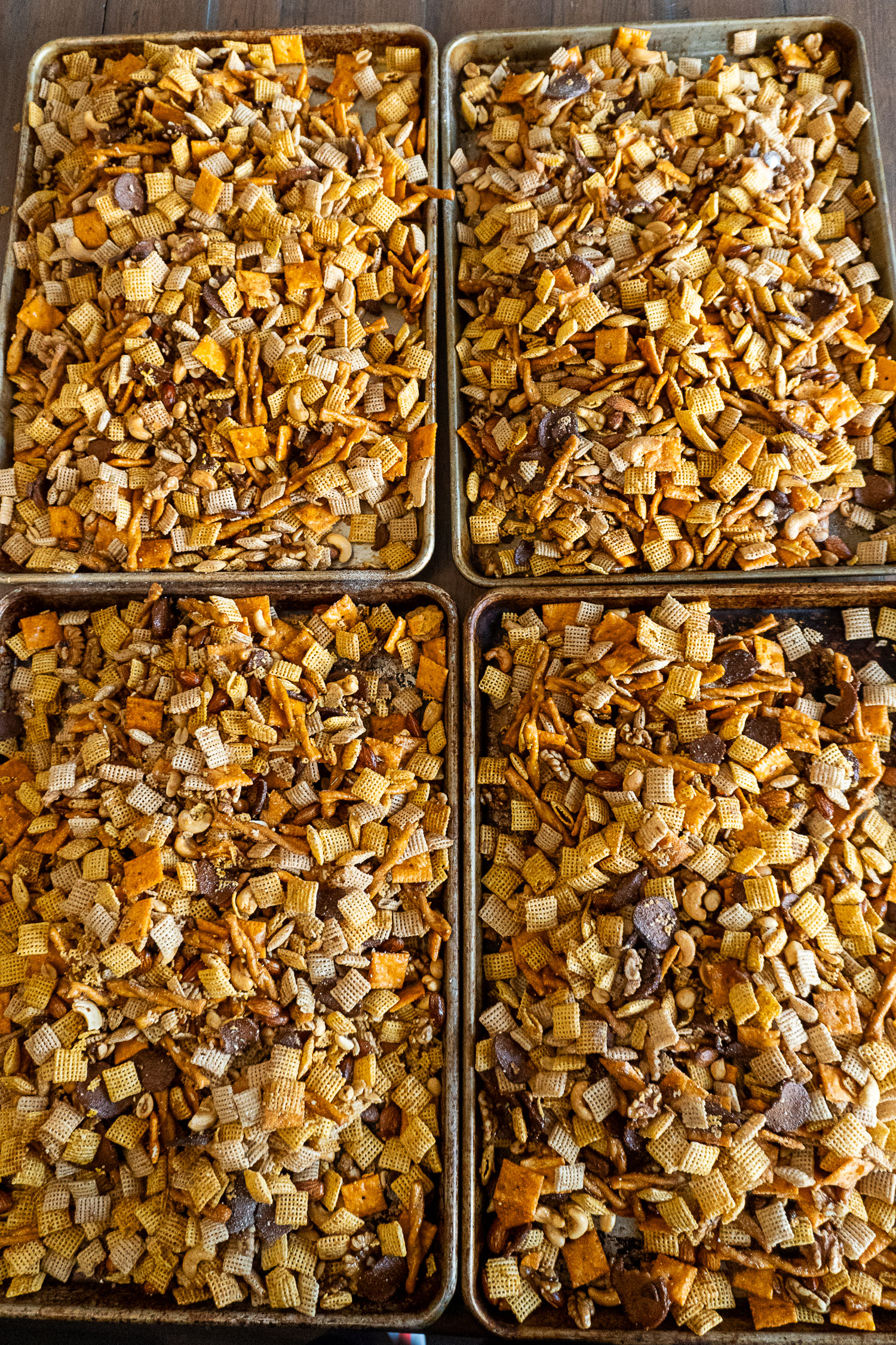 4 sheet pans of chex mix ready to bake in the oven.