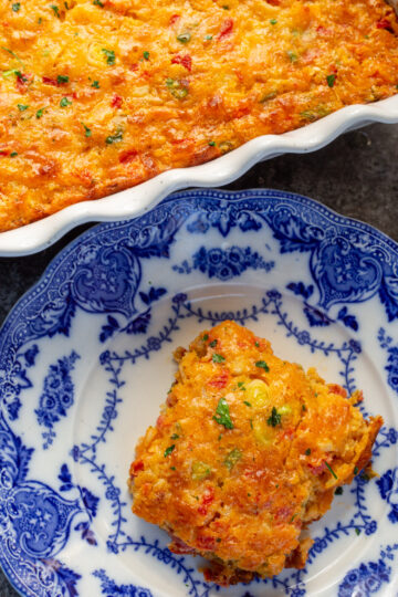 A golden brown square of crawfish cornbread on a beautiful blue plate.