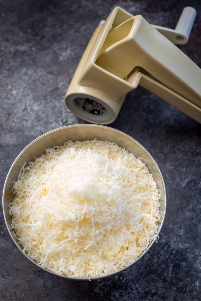 A bowl of parmesan cheese and a cheese grater