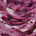 mashed purple sweet potato recipe on a white plate with honey butter drizzle