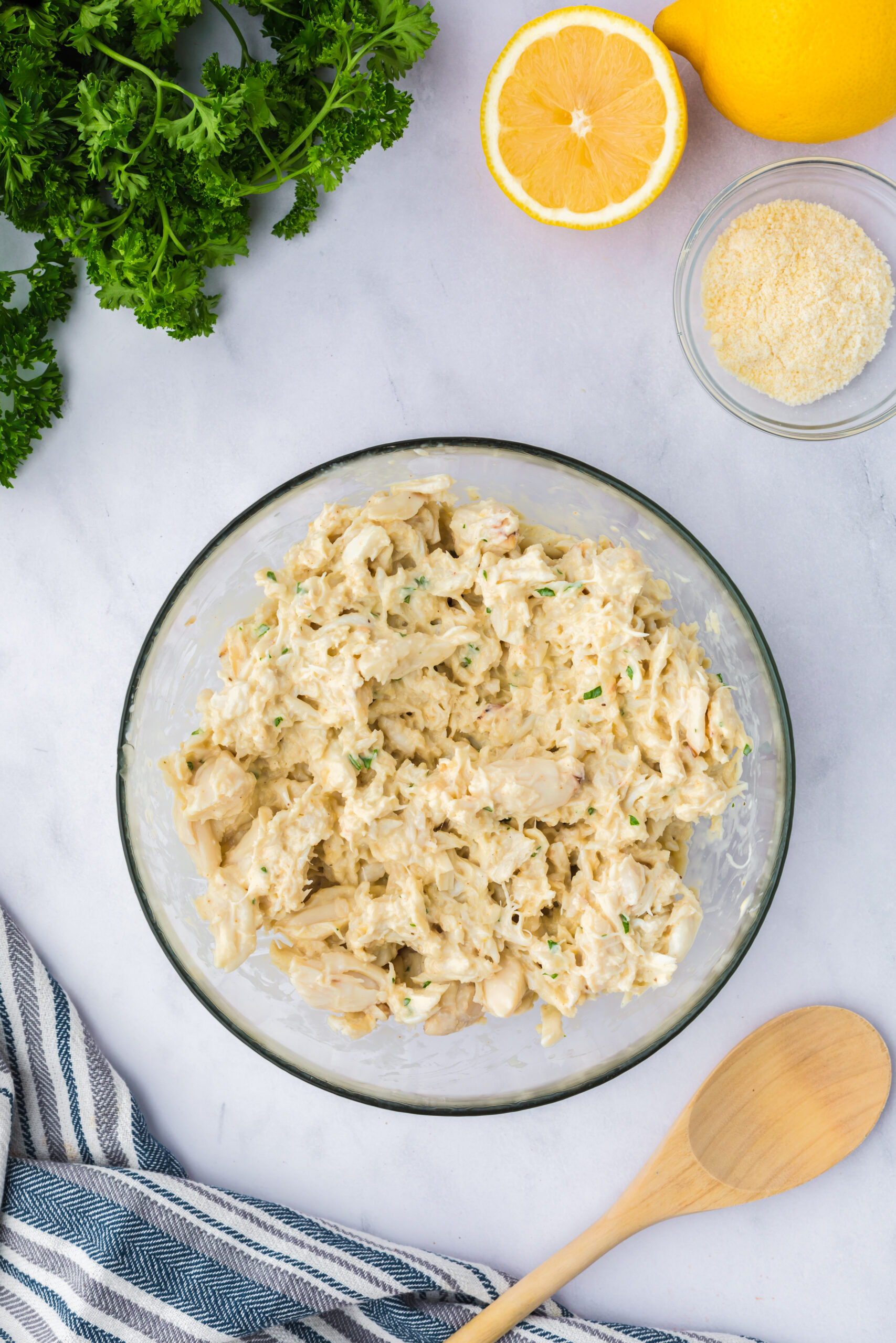a glass bowl on a table filled with crab meat that has been mixed and blended into the imperial sauce