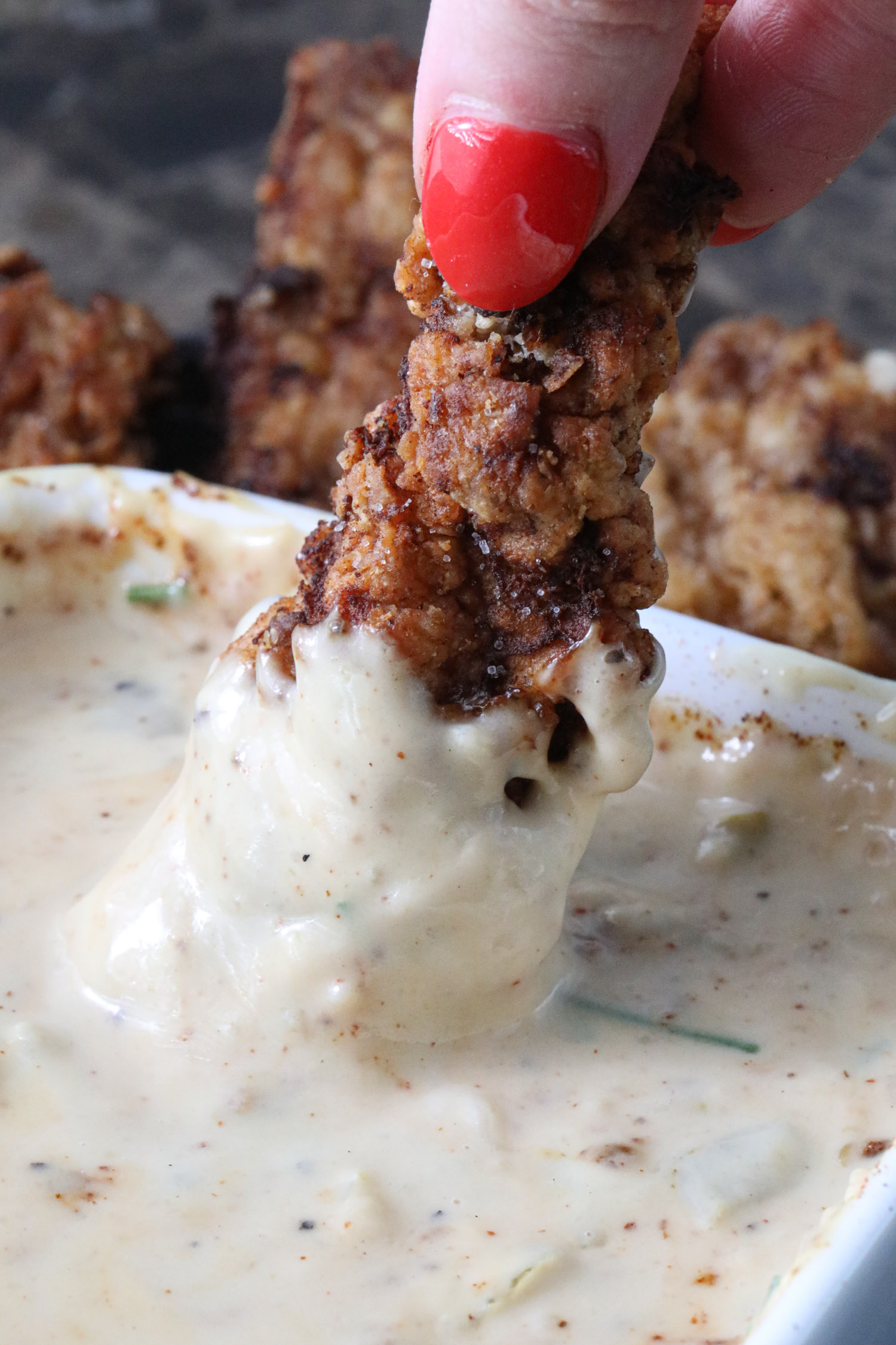 A steak finger dipped in a bowl of white gravy