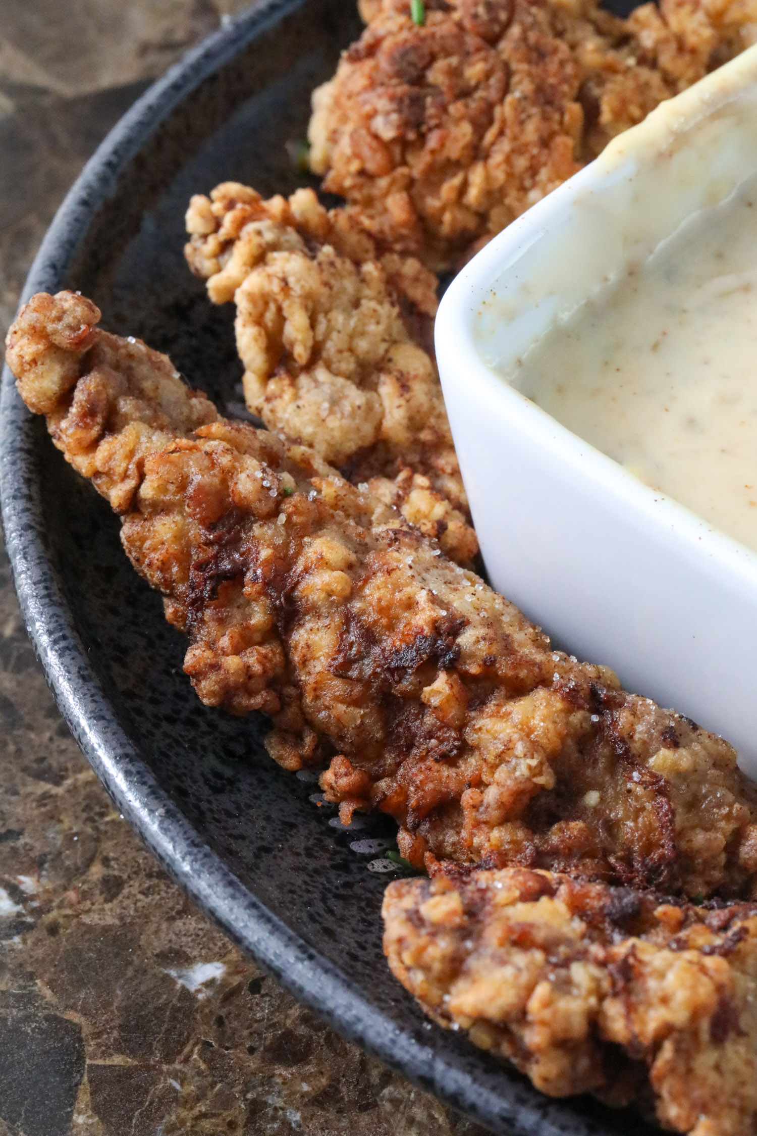 a plate of steak fingers with a bowl of white cream gravy