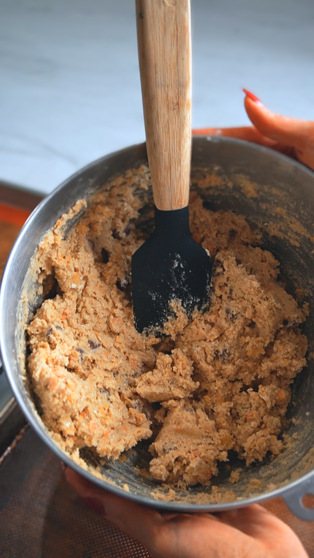 a close-up shot of a mixing bowl with cowboy cookie ingredients mixed together and a plastic mixing spoon sits in the mixing bowl as well