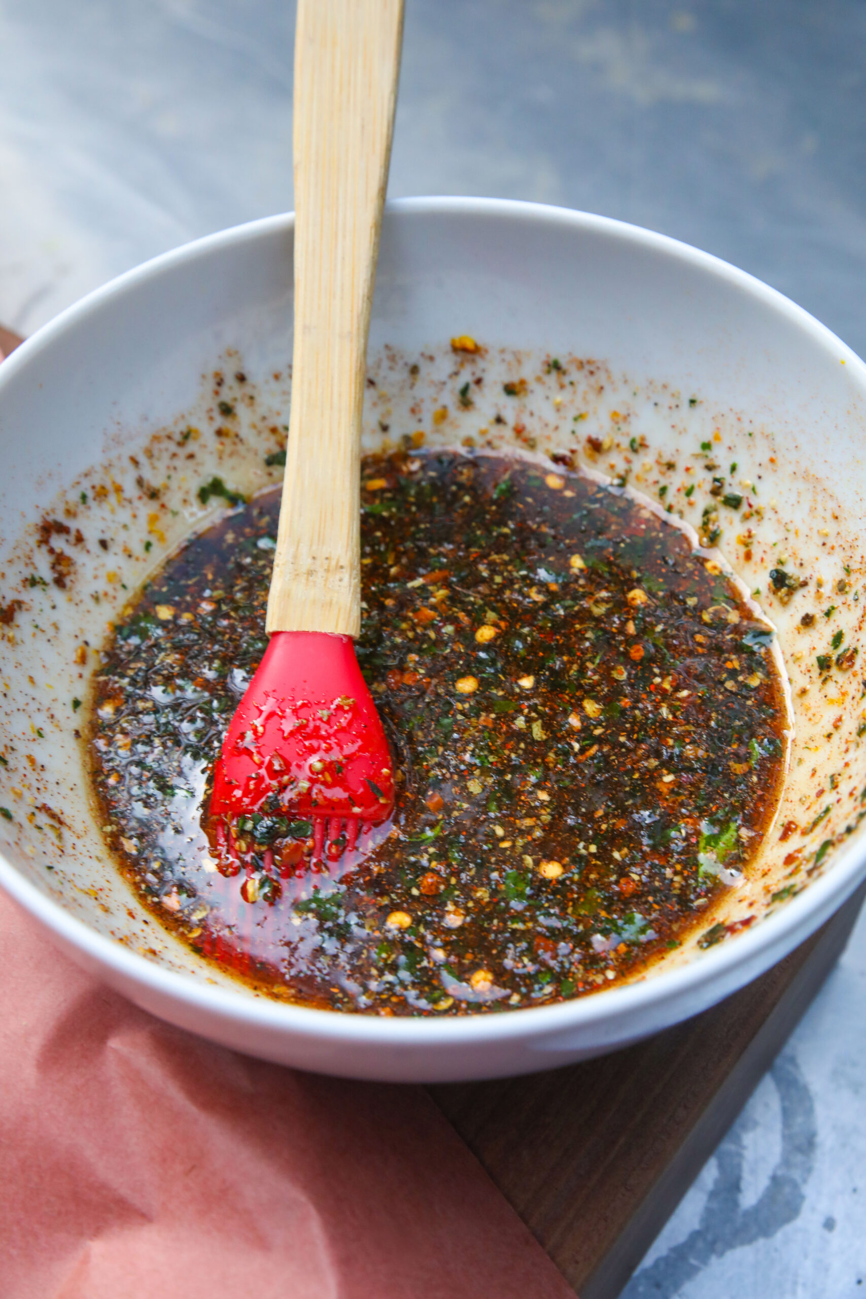 a bowl of maple glaze with herbs, chile flakes, and mandarin 