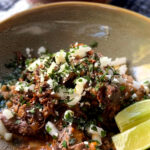 a mexican beef chuck roast in a green bowl with limes