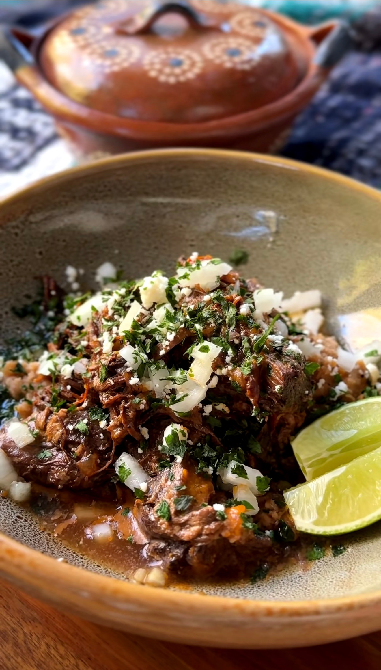 a mexican beef chuck roast in a green bowl with limes