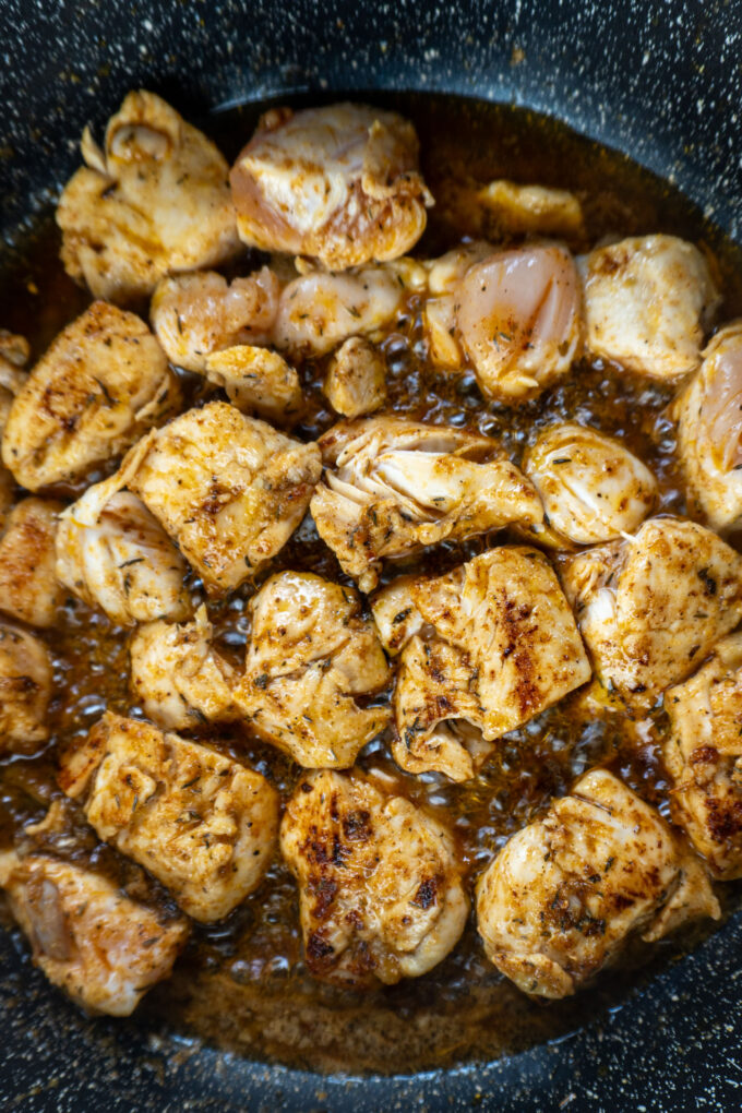 Pieces of chicken cooking in cajun butter in a hot skillet
