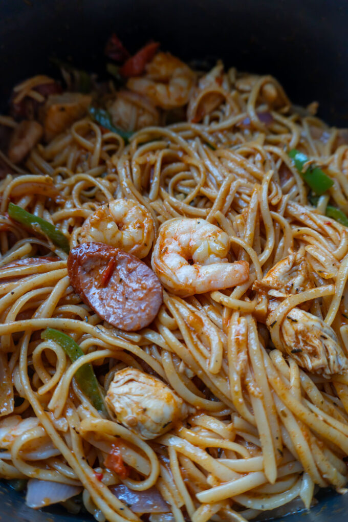 A big pot of a pasta dish with shrimp, sausage, chicken, and veggies in a cajun butter sauce.