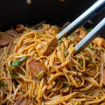 A gorgeous pot full of glistening linguine, coated in Cajun butter sauce, topped with sausage and shrimp
