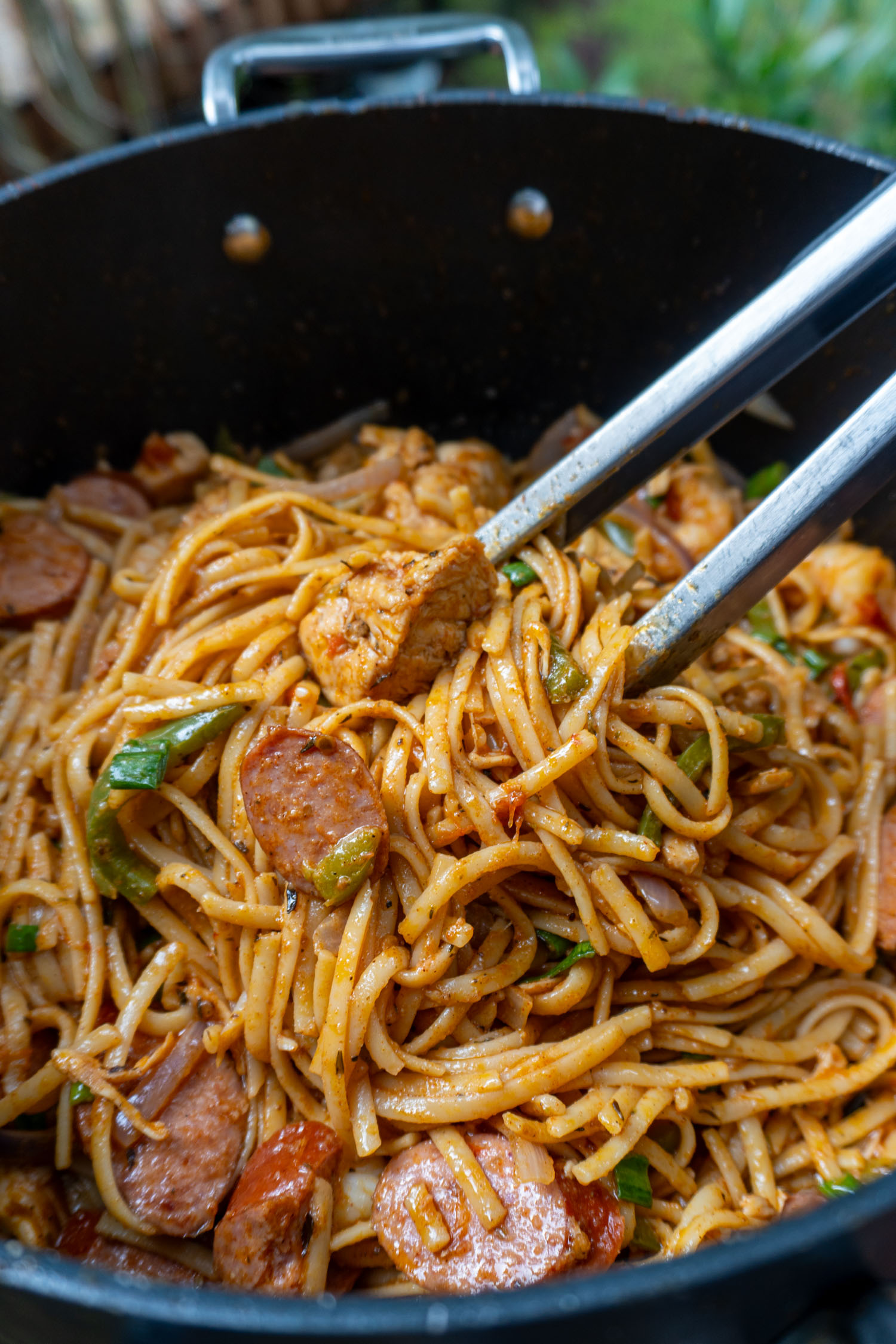 A gorgeous pot full of glistening linguine, coated in Cajun butter sauce, topped with sausage and shrimp 