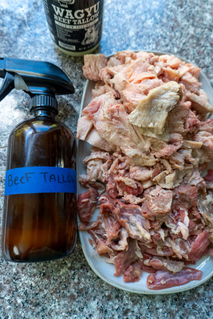 A spray bottle of beef tallow next to a plate of trimmings.