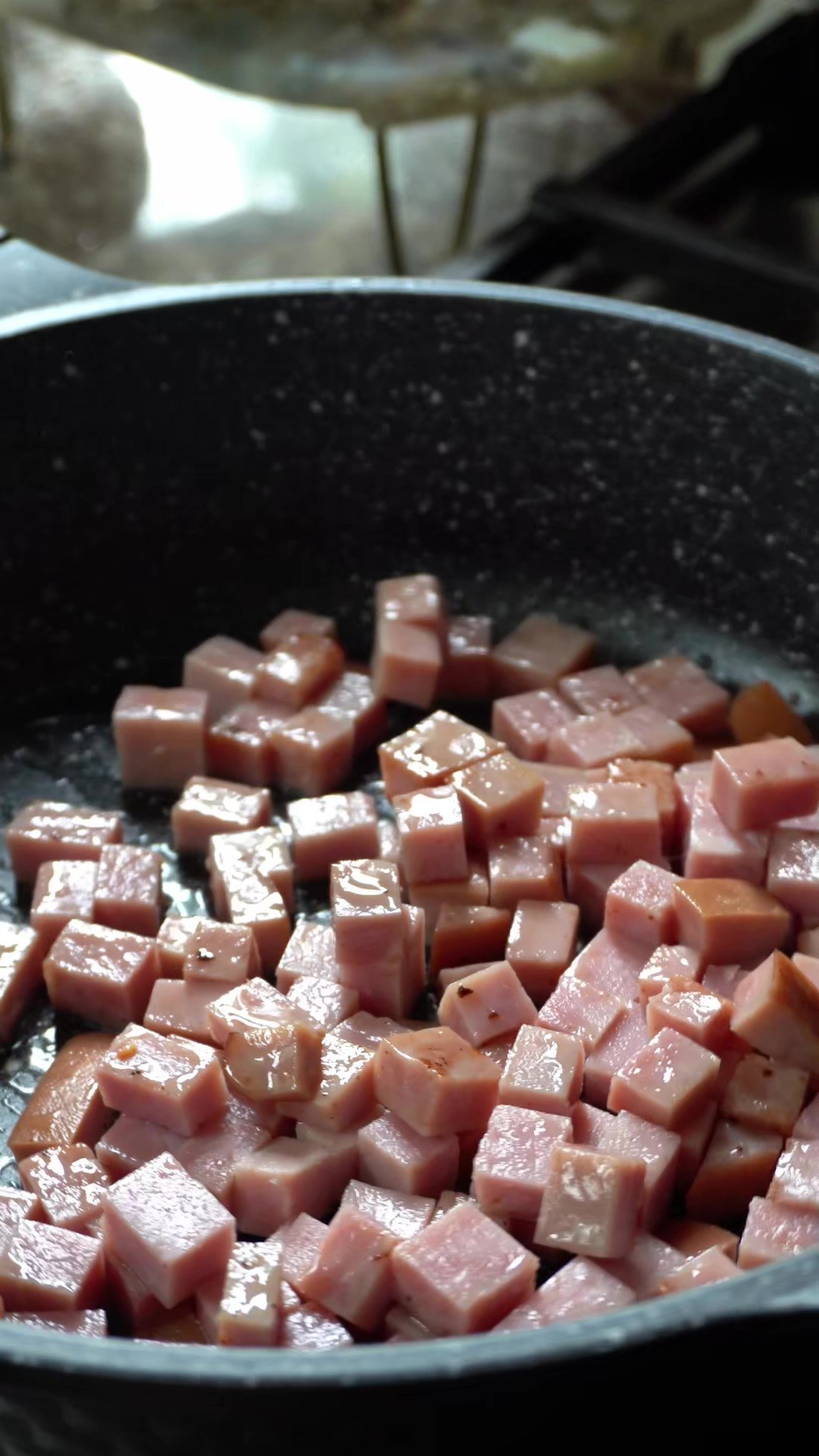 Ham cubes cooking in a black skillet