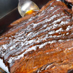 sliced brisket in a roasting pan drizzled with pan juices