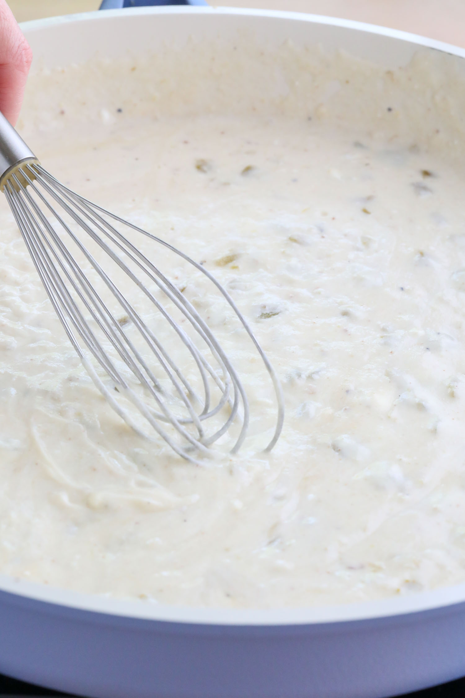 A whisk whisking the green chile enchiladas sauce together