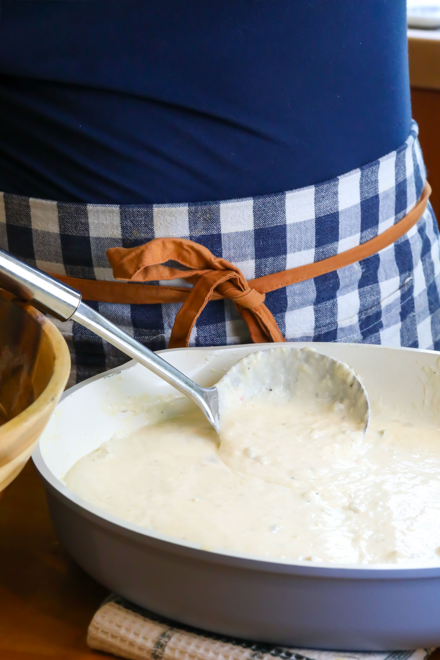 A ladel held up to demonstrate the sauce is thickened and ready for pouring over the dish.