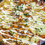 close up of poblano sauce poured over cooked garlic shrimp drizzled with crema