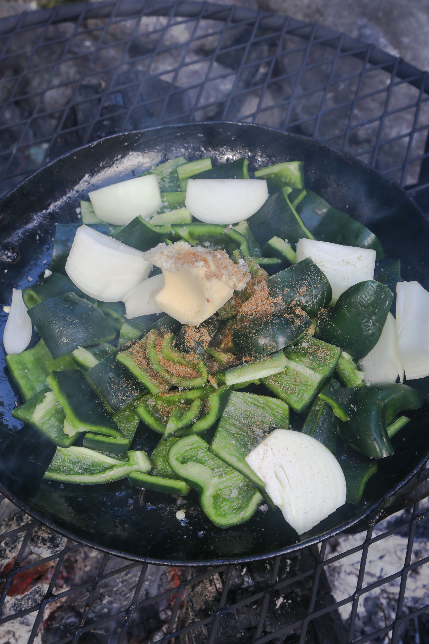 choped poblano pepper, onion, cumin, and butter sizzling in a pan over a fire