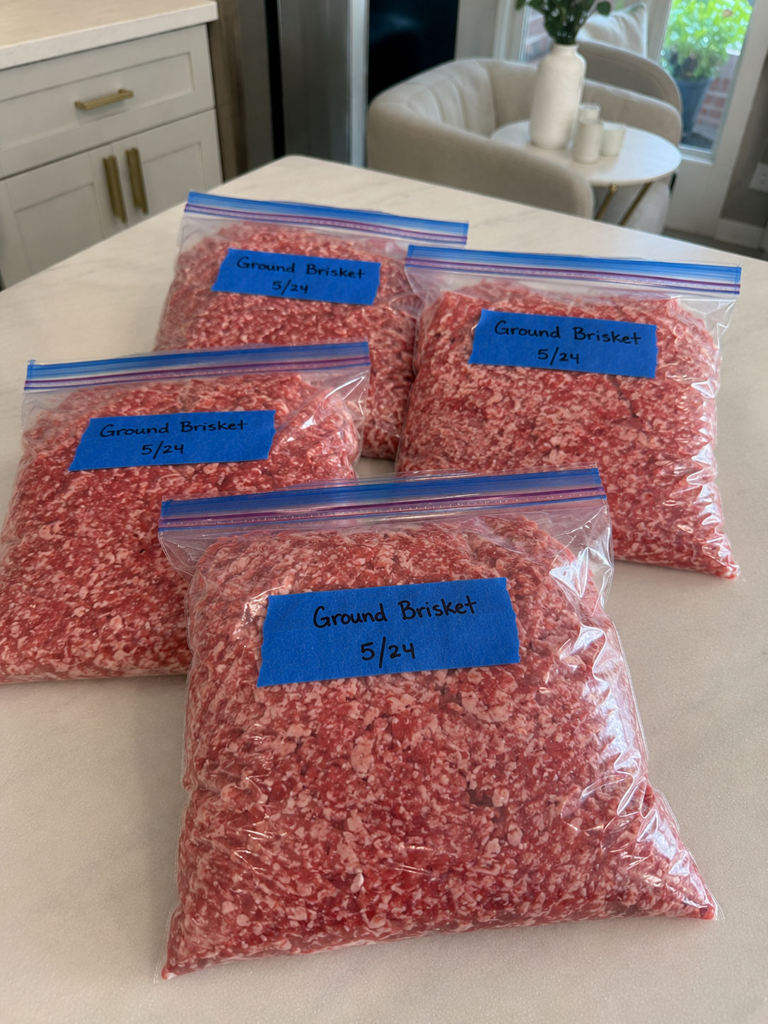 freezer bags full of ground brisket meat labeled with blue tape.