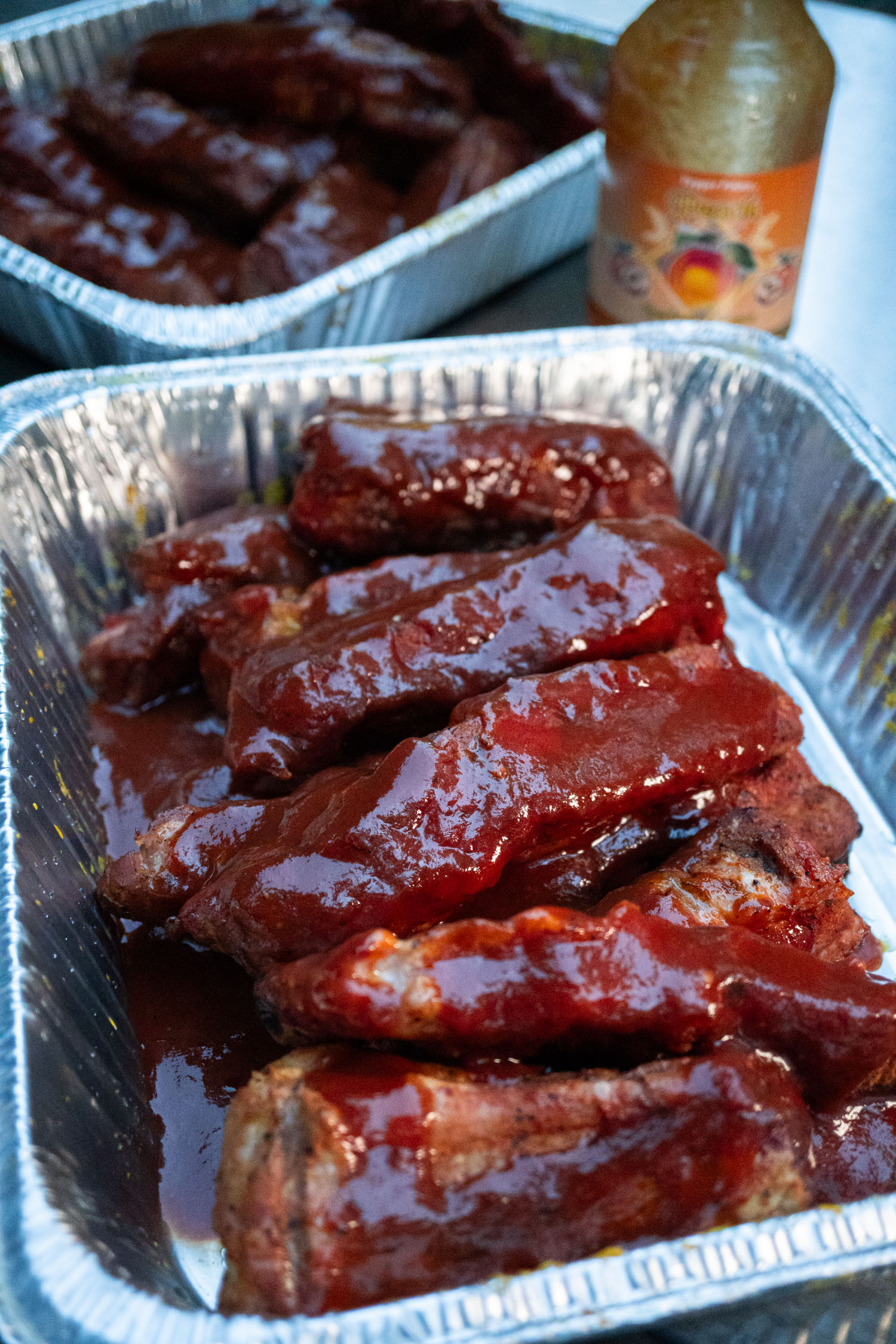 A pan full of cooked pork ribs sauced with peach barbecue sauce
