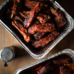 Smoked pork ribs in a half pan on a wooden table